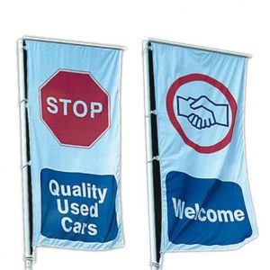 One highway spar flag with a stop sign and quality used cars printed in a blue box underneath and another flag with a greeting icon and a welcome caption in a blue box underneath